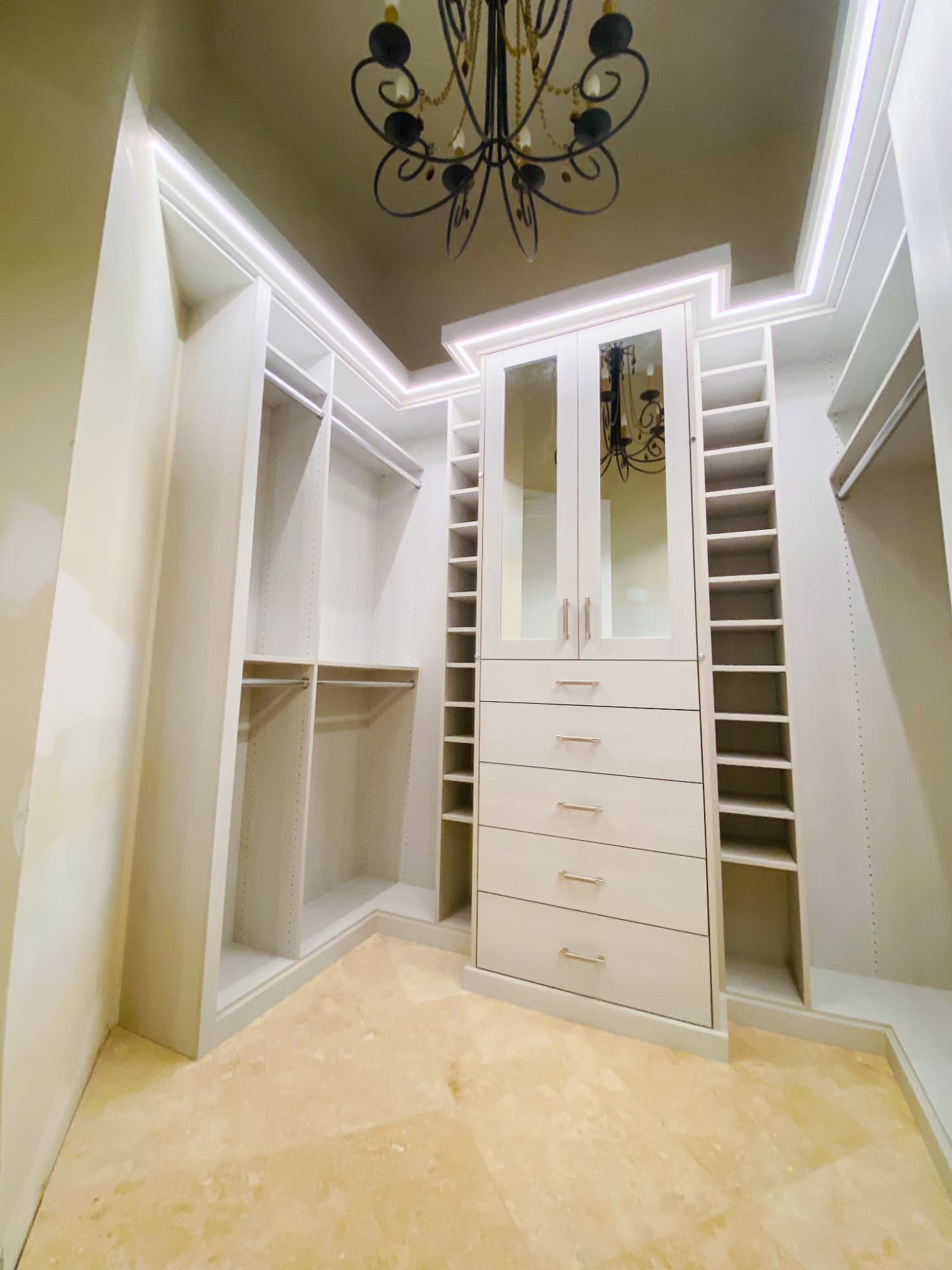 White walk-in closet with LED lit crown and mirrored doors