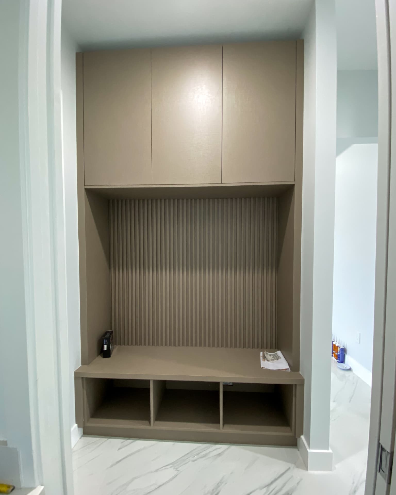 Taupe entry built-in with bench and fluted panel